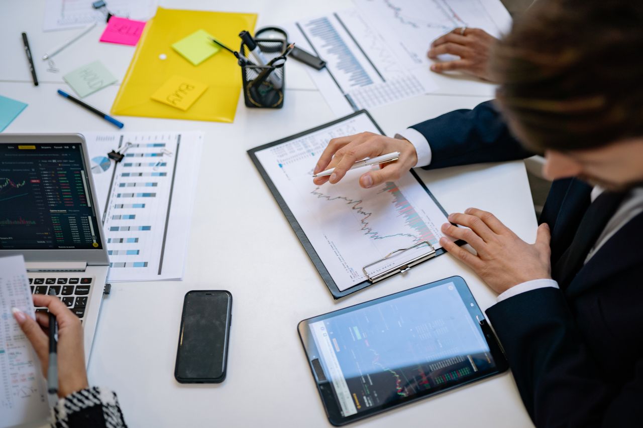 about-01 Team reviewing financial charts and digital data on tablets in an office setting.
